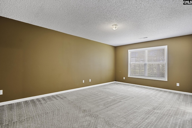 spare room featuring a textured ceiling, carpet floors, and baseboards