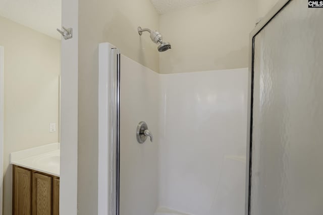 bathroom featuring a shower stall, vanity, and a textured ceiling