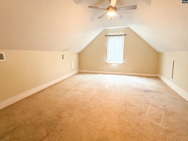 additional living space with light colored carpet, a textured ceiling, ceiling fan, baseboards, and lofted ceiling