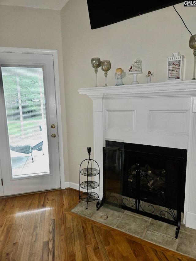detailed view of a fireplace with flush hearth, wood finished floors, and baseboards
