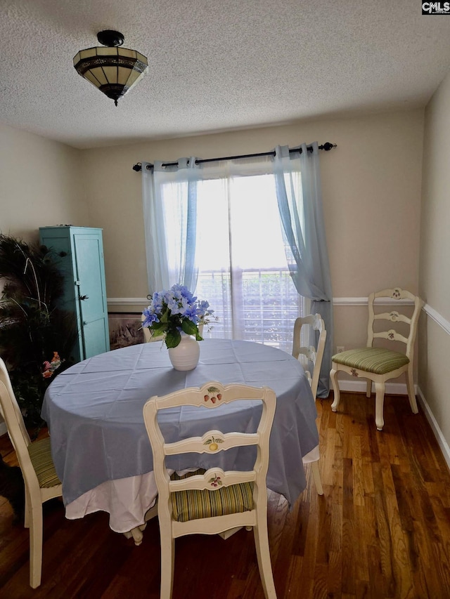 dining area with a textured ceiling, wood finished floors, and baseboards