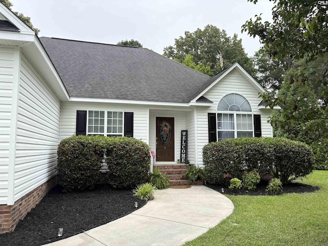view of front of property featuring roof with shingles and a front yard