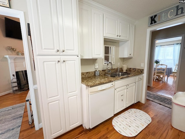 kitchen with dishwasher, a sink, light wood-style floors, white cabinets, and a textured ceiling