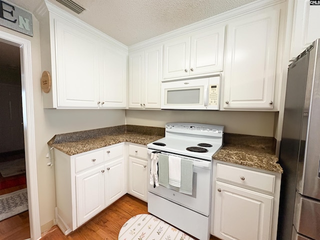 kitchen with white appliances, dark countertops, light wood-style floors, white cabinetry, and a textured ceiling