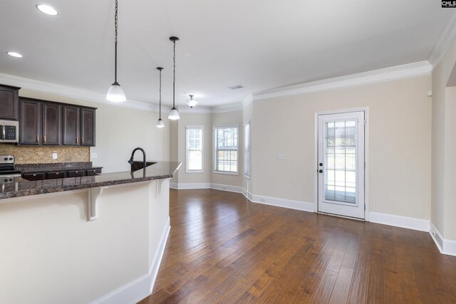 680 Curlew Cir, Sumter, SC 29150 - kitchen with appliances with stainless steel finishes, a breakfast bar, dark brown cabinets, ornamental molding, and dark stone countertops