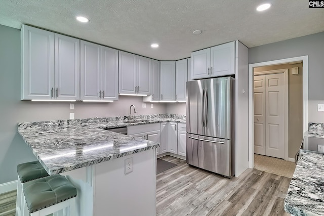 1240 Windmill Rd, Leesville, SC 29070 - kitchen featuring freestanding refrigerator, a peninsula, white cabinetry, light wood-style flooring, and recessed lighting