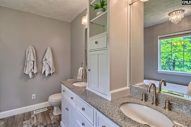 1240 Windmill Rd, Leesville, SC 29070 - full bathroom with double vanity, toilet, a textured ceiling, baseboards, and wood finished floors