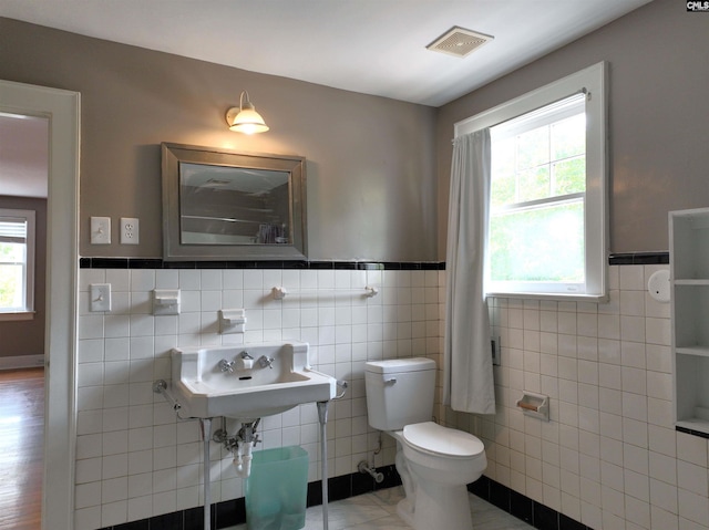 3925 Rosewood Dr, Columbia, SC 29205 - bathroom featuring tile walls, toilet, a wainscoted wall, and a sink