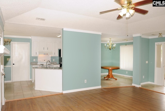 kitchen with ceiling fan, under cabinet range hood, light wood finished floors, white cabinets, and a chandelier