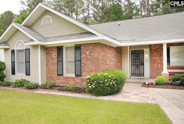 view of front of house featuring brick siding, a front lawn, roof with shingles, and a porch
