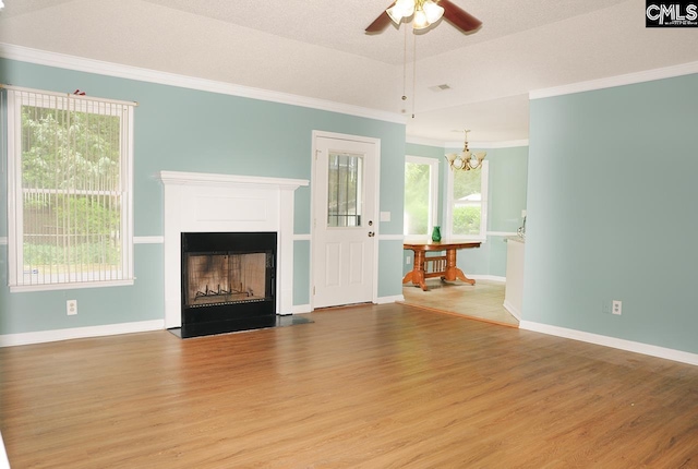 unfurnished living room featuring wood finished floors, crown molding, a ceiling fan, a chandelier, and baseboards