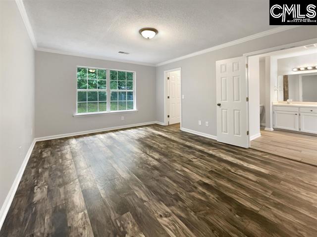 unfurnished bedroom with crown molding, dark wood-style floors, baseboards, a sink, and a textured ceiling