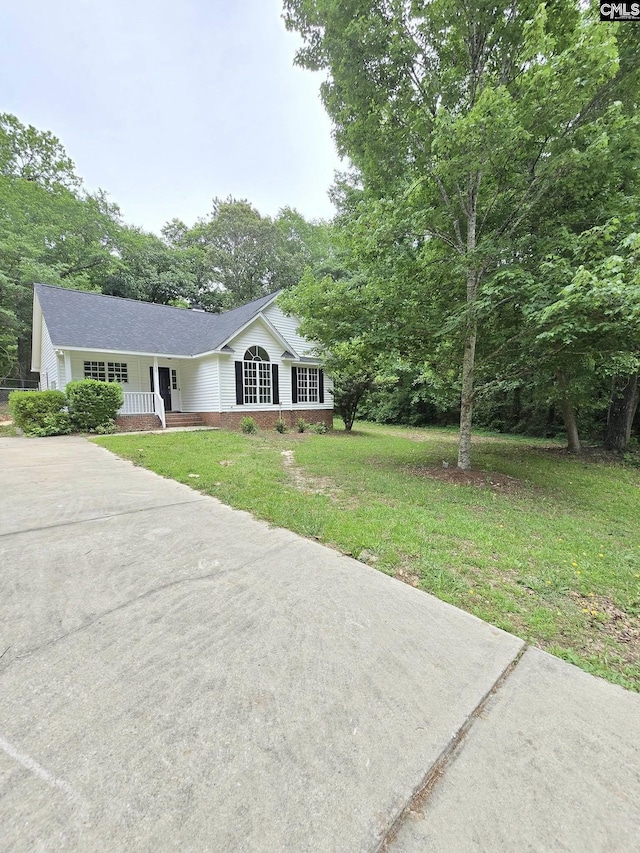 single story home with concrete driveway, a front lawn, covered porch, and a shingled roof