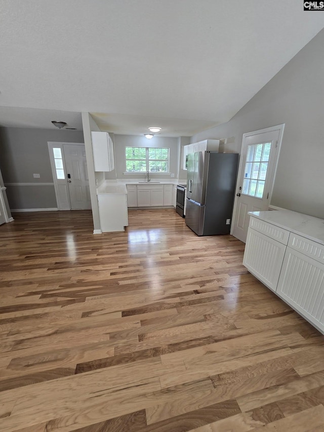 kitchen featuring stainless steel fridge with ice dispenser, a sink, light wood-style flooring, white cabinets, and light countertops