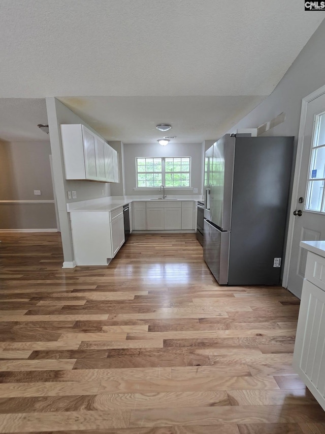 kitchen with stainless steel fridge with ice dispenser, electric range, light wood finished floors, light countertops, and white cabinets