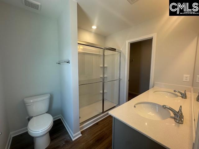 1023 Skyline Rd, Columbia, SC 29229 - full bathroom with toilet, wood finished floors, a stall shower, baseboards, and double vanity
