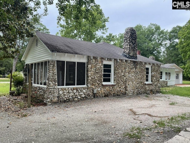 2803 Stewart St, Camden, SC 29020 - view of front of home with stone siding, a chimney, a sunroom, and roof with shingles