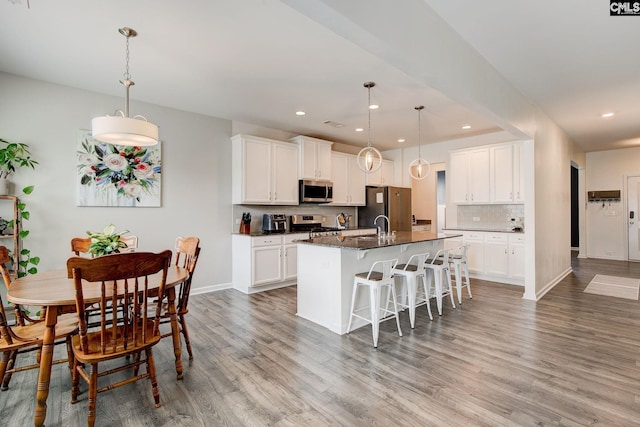 121 Bridgeport Rd, Elgin, SC 29045 - kitchen with stainless steel appliances, a kitchen island with sink, a breakfast bar, light wood-type flooring, and recessed lighting