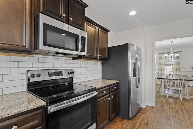 150 Ventnor Ave, Chapin, SC 29036 - kitchen featuring appliances with stainless steel finishes, wood finished floors, a chandelier, dark brown cabinets, and light stone countertops