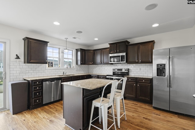 150 Ventnor Ave, Chapin, SC 29036 - kitchen with stainless steel appliances, dark brown cabinetry, a sink, light stone countertops, and light wood-style flooring