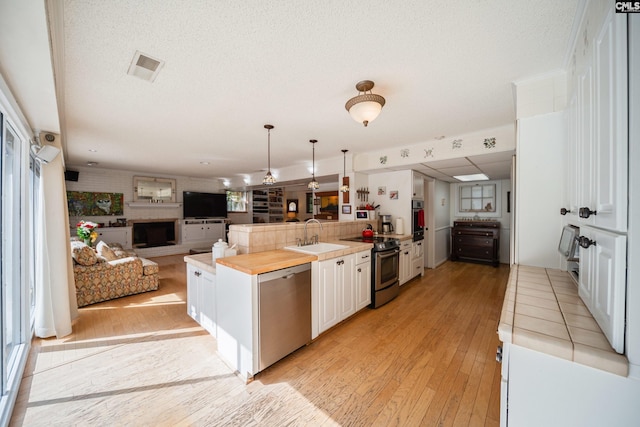 3100 Grace Hill Rd, Columbia, SC 29204 - kitchen with appliances with stainless steel finishes, a sink, light wood-type flooring, a peninsula, and a textured ceiling