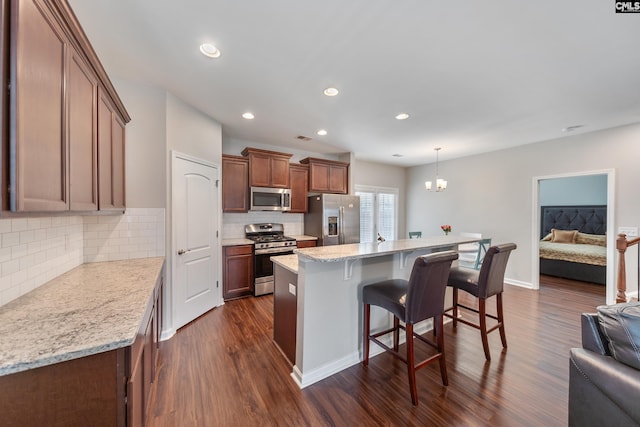 1148 Declaration Dr, Elgin, SC 29045 - kitchen with appliances with stainless steel finishes, dark wood-type flooring, a kitchen bar, open floor plan, and decorative backsplash