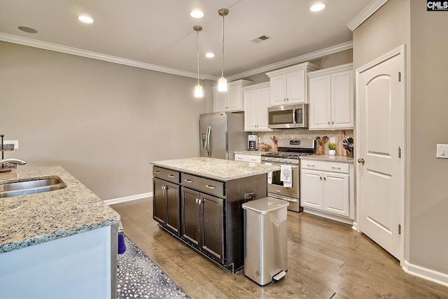 335 Hollow Cove Rd, Chapin, SC 29036 - kitchen featuring appliances with stainless steel finishes, a sink, crown molding, white cabinetry, and decorative backsplash