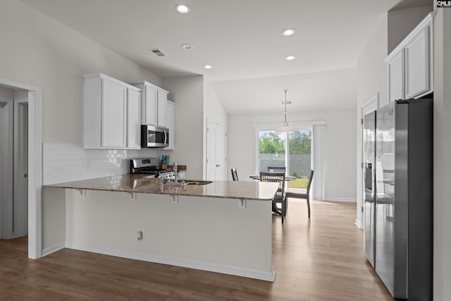 627 Cheehaw Ave, West Columbia, SC 29170 - kitchen with stainless steel appliances, a peninsula, stone counters, tasteful backsplash, and wood finished floors