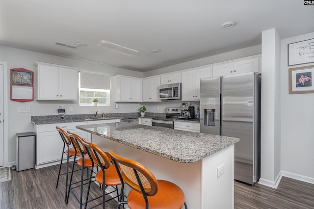 646 Penfolds Way, Blythewood, SC 29016 - kitchen featuring appliances with stainless steel finishes, a kitchen island, white cabinets, dark wood-style floors, and a breakfast bar area