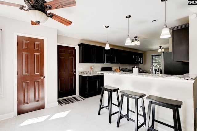 220 Pine Grove Rd, Lugoff, SC 29078 - kitchen featuring dark cabinets, baseboards, freestanding refrigerator, a kitchen bar, and a peninsula