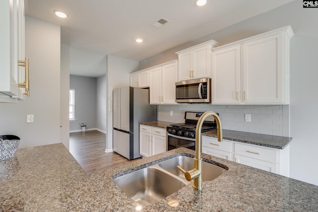 724 Channing Creek Ln, Lexington, SC 29072 - kitchen featuring appliances with stainless steel finishes, wood finished floors, white cabinetry, decorative backsplash, and a sink