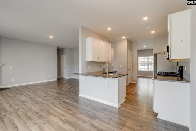 724 Channing Creek Ln, Lexington, SC 29072 - kitchen with dark stone countertops, light wood finished floors, backsplash, white cabinets, and recessed lighting