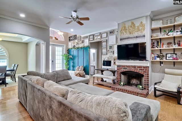 117 Shoal Creek Ln, Blythewood, SC 29016 - living room featuring arched walkways, ornamental molding, ceiling fan, a fireplace, and light wood-type flooring