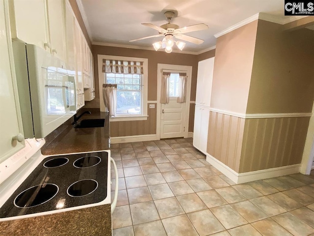 2825 Pruitt Dr, Columbia, SC 29204 - kitchen with a sink, white microwave, range with electric cooktop, light tile patterned flooring, and wainscoting