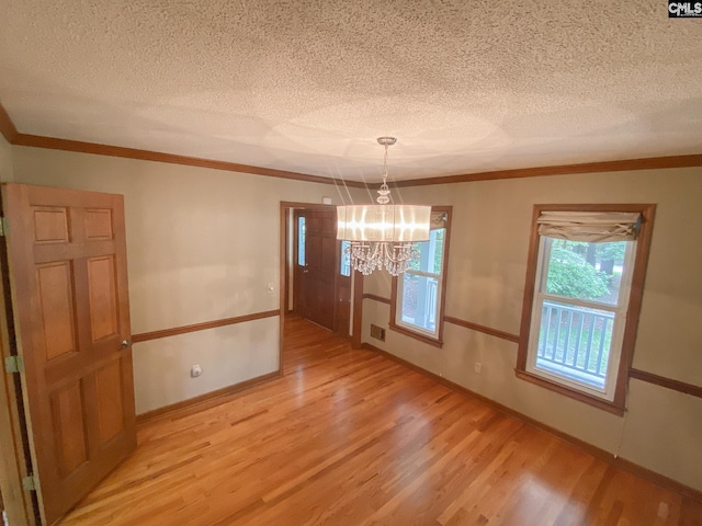 141 Runneymede Dr, Blythewood, SC 29016 - unfurnished dining area with light wood-type flooring, a chandelier, a textured ceiling, ornamental molding, and baseboards