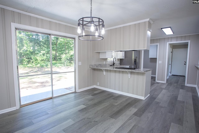 4513 Bonnie Forest Blvd, Columbia, SC 29210 - kitchen with crown molding, stainless steel fridge, a peninsula, a chandelier, and dark wood-style floors