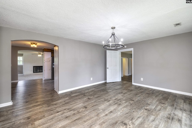 137 Wingate St, Darlington, SC 29532 - empty room featuring dark wood finished floors, arched walkways, a chandelier, baseboards, and a textured ceiling
