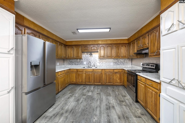 137 Wingate St, Darlington, SC 29532 - kitchen featuring stainless steel appliances, brown cabinetry, under cabinet range hood, a textured ceiling, and wood finished floors