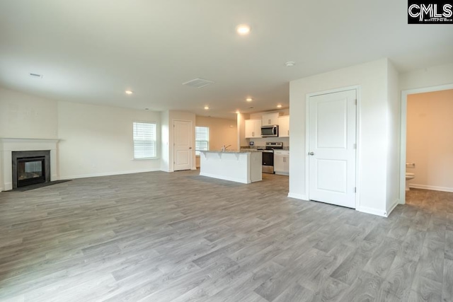 158 Dunham Rd, Columbia, SC 29209 - unfurnished living room with light wood finished floors, recessed lighting, a fireplace with flush hearth, and baseboards