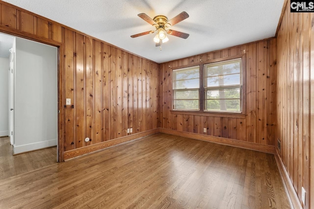 200 Shady Ln, Cayce, SC 29033 - unfurnished room with light wood finished floors, a ceiling fan, baseboards, wood walls, and a textured ceiling