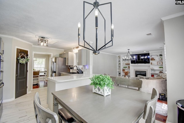 113 Dutch Oaks Dr, Irmo, SC 29063 - dining room featuring light wood-style flooring, a chandelier, ornamental molding, a fireplace, and a textured ceiling