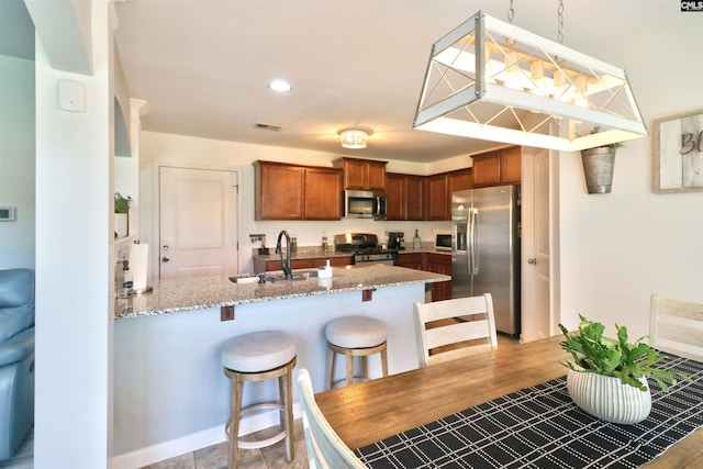 542 Pineberry Ct, West Columbia, SC 29170 - kitchen featuring appliances with stainless steel finishes, a sink, a peninsula, a breakfast bar area, and light stone countertops
