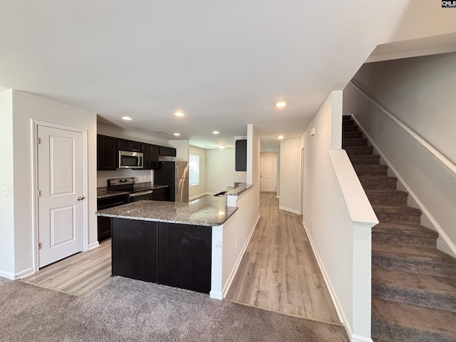 184 Windfall Rd, Blythewood, SC 29016 - kitchen with stainless steel appliances, light wood-type flooring, a peninsula, light stone countertops, and baseboards