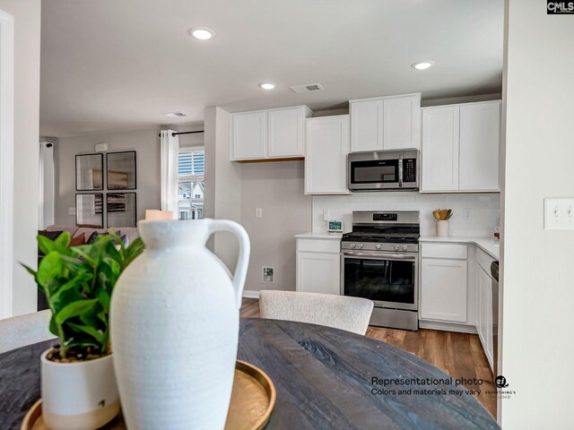 219 Bones Rd, Gilbert, SC 29054 - kitchen with appliances with stainless steel finishes, wood finished floors, white cabinets, decorative backsplash, and recessed lighting