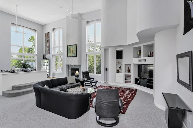 520 Sail Point Way, Columbia, SC 29212 - carpeted living area featuring a ceiling fan, built in shelves, a glass covered fireplace, a high ceiling, and baseboards