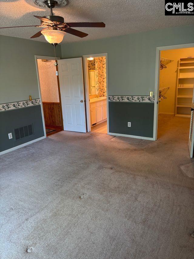 100 Clee Hill Ct, Irmo, SC 29063 - unfurnished bedroom featuring carpet, a spacious closet, a textured ceiling, baseboards, and a ceiling fan