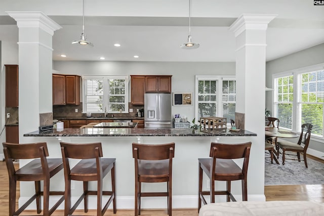 128 Van Der Horst Dr, Columbia, SC 29229 - kitchen featuring stainless steel fridge with ice dispenser, ornate columns, light wood finished floors, a peninsula, and a breakfast bar area