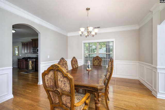 22 Genesis Ln, Camden, SC 29020 - dining area featuring light wood finished floors, a chandelier, ornamental molding, arched walkways, and a wainscoted wall