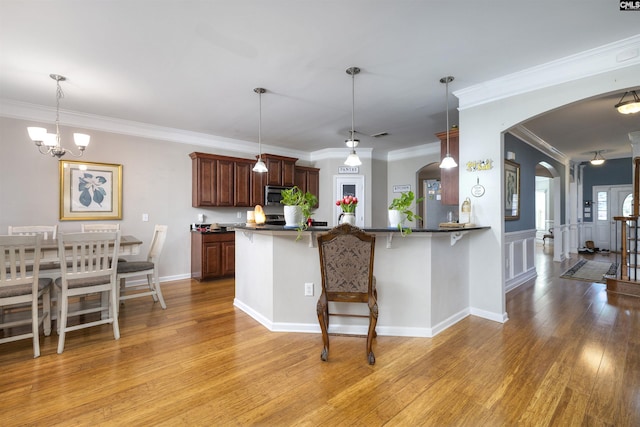 22 Genesis Ln, Camden, SC 29020 - kitchen with stainless steel microwave, arched walkways, a breakfast bar area, light wood finished floors, and decorative light fixtures