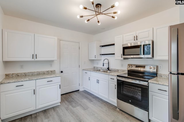 1817 English Ave, Columbia, SC 29204 - kitchen featuring appliances with stainless steel finishes, a sink, a chandelier, light wood-type flooring, and white cabinetry